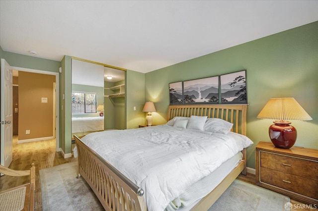 bedroom with a spacious closet, light hardwood / wood-style floors, and a closet