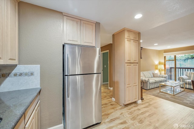 kitchen with light brown cabinets, light hardwood / wood-style flooring, and stainless steel refrigerator