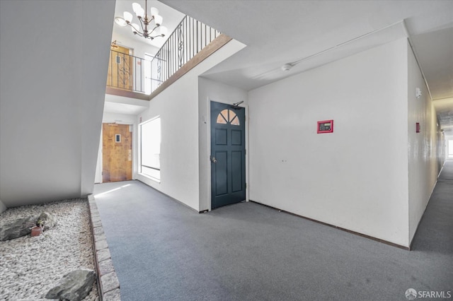 carpeted entryway with a high ceiling and a notable chandelier