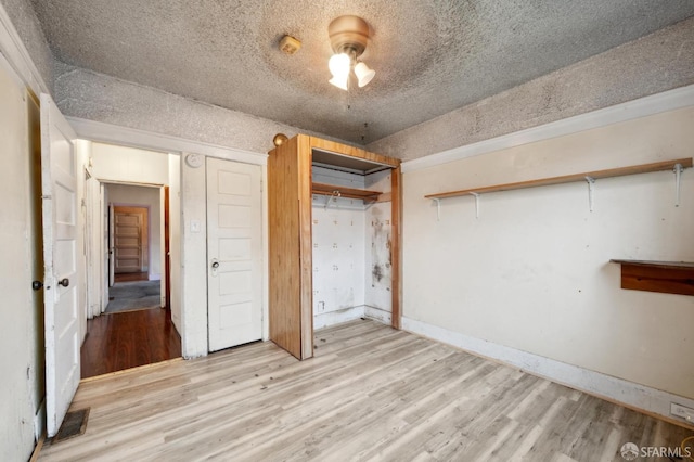 unfurnished bedroom with a textured ceiling, a closet, visible vents, and light wood-style floors