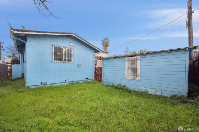 back of house with crawl space and a lawn