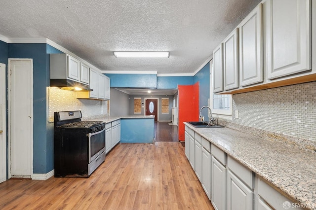 kitchen featuring light wood finished floors, white cabinets, stainless steel gas range, crown molding, and a sink