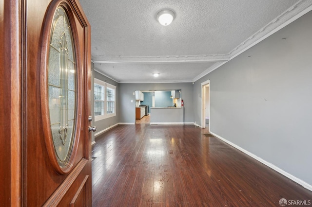 interior space featuring a textured ceiling, baseboards, wood finished floors, and ornamental molding