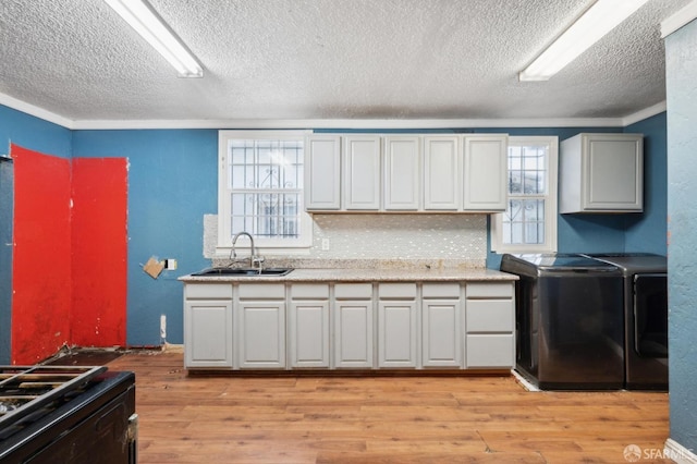 kitchen with light wood-style flooring, light countertops, a sink, and independent washer and dryer