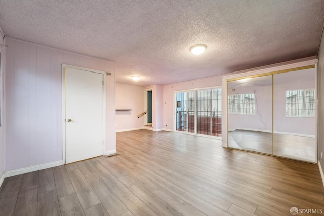 spare room with baseboards, visible vents, stairs, a textured ceiling, and light wood-type flooring