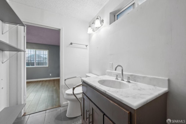 bathroom with a textured ceiling, toilet, and vanity