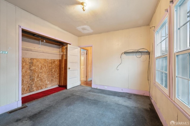 unfurnished bedroom with visible vents and dark carpet