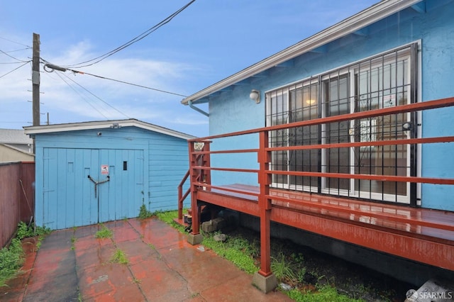 exterior space featuring an outbuilding, a patio, a wooden deck, and a storage unit