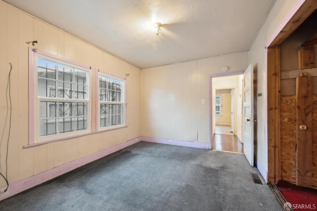 spare room featuring dark colored carpet and visible vents