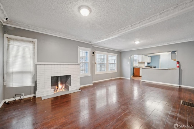 unfurnished living room featuring dark wood-type flooring, crown molding, a fireplace, and baseboards