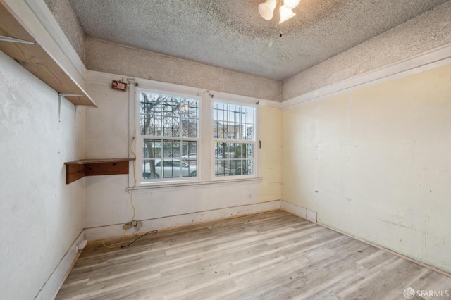 spare room featuring light wood-type flooring and a textured ceiling