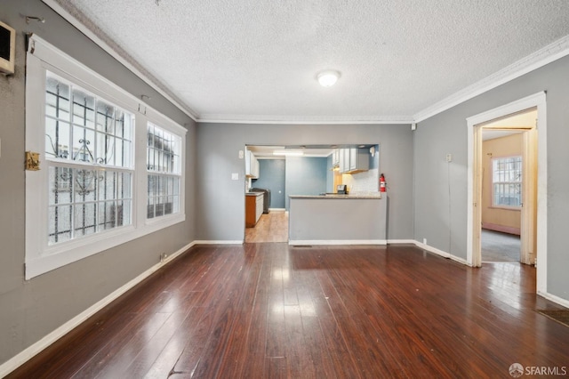 spare room featuring baseboards, ornamental molding, dark wood finished floors, and a textured ceiling