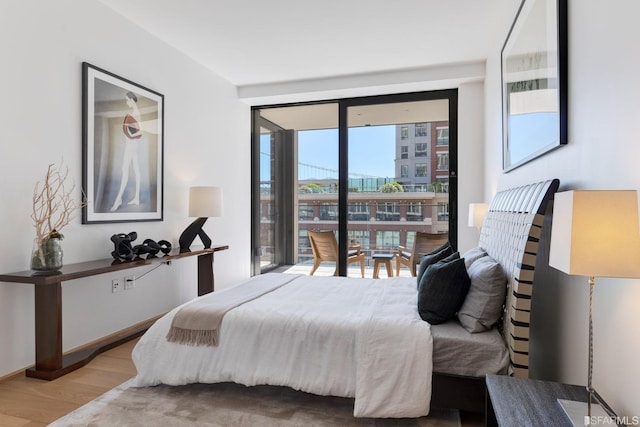 bedroom with wood-type flooring and a wall of windows