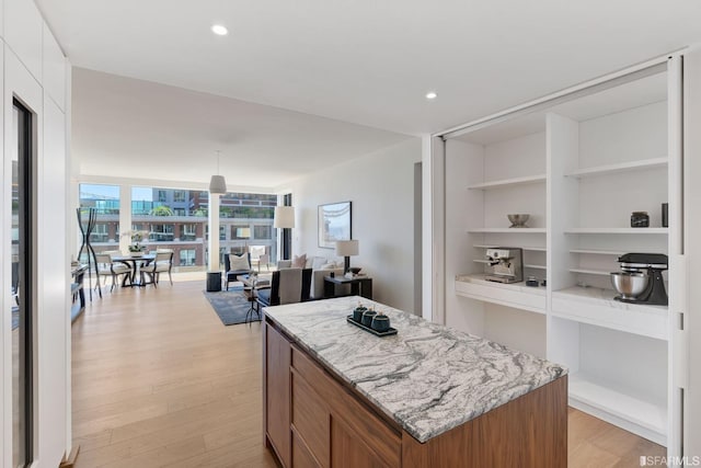 kitchen with pendant lighting, a center island, white cabinets, built in features, and light wood-type flooring