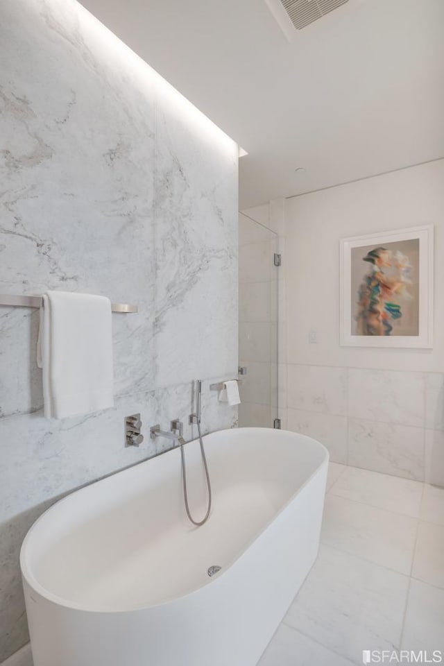 bathroom featuring a bathing tub, tile patterned flooring, and tile walls