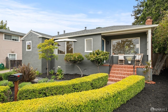 view of front of property featuring stucco siding, fence, and a chimney