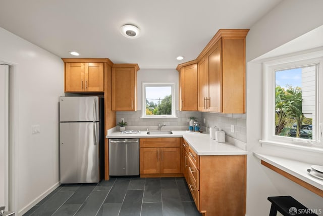 kitchen featuring tasteful backsplash, a sink, stainless steel appliances, light countertops, and brown cabinetry