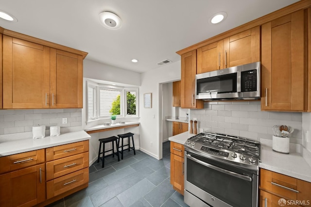 kitchen featuring visible vents, stainless steel appliances, light countertops, baseboards, and backsplash