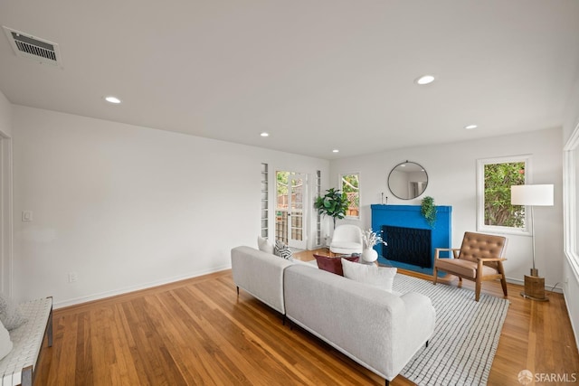 living room featuring visible vents, baseboards, a wealth of natural light, and light wood-style floors