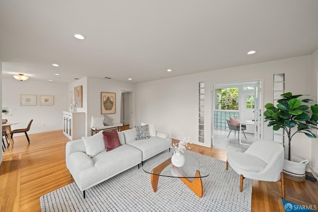 living room with recessed lighting, baseboards, and light wood-style floors