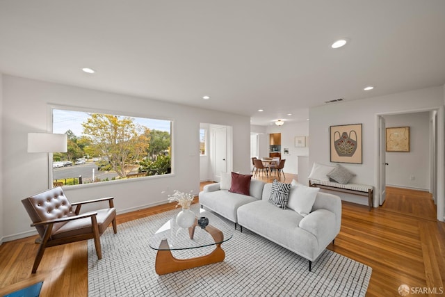 living area with recessed lighting, visible vents, and wood finished floors