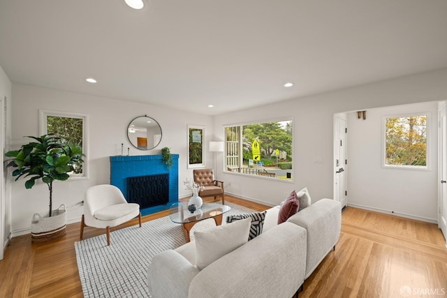 living area featuring a fireplace with flush hearth, light wood-type flooring, recessed lighting, and baseboards