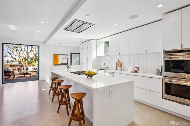 kitchen featuring sink, white cabinetry, stainless steel appliances, a kitchen breakfast bar, and a center island