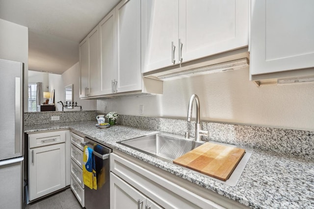 kitchen featuring light stone countertops, appliances with stainless steel finishes, white cabinets, and a sink