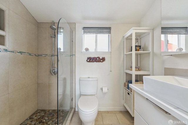 bathroom featuring toilet, vanity, baseboards, tile patterned floors, and walk in shower