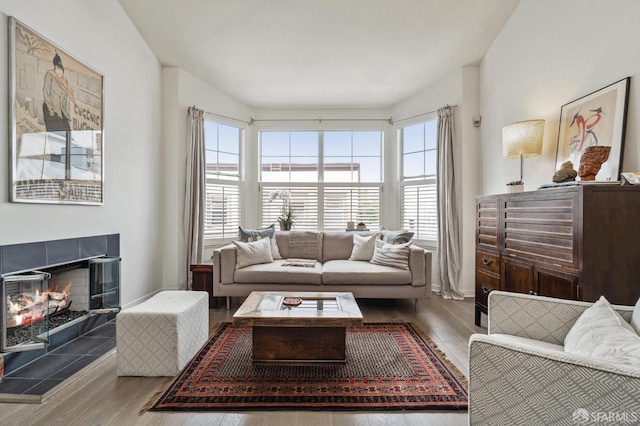 living room featuring light wood finished floors, a tile fireplace, and baseboards