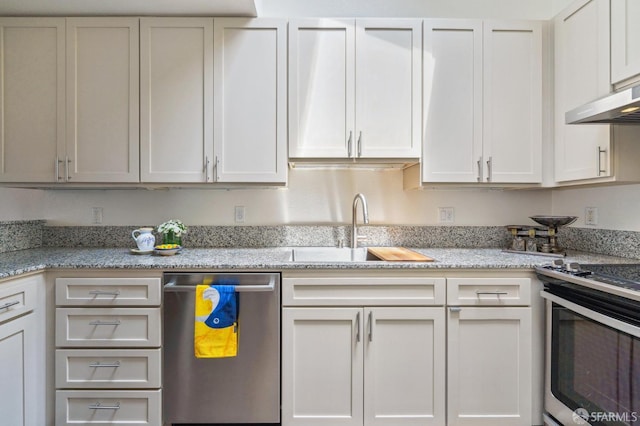 kitchen featuring appliances with stainless steel finishes, a sink, white cabinetry, and light stone countertops