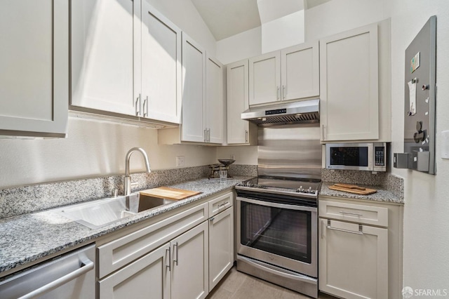 kitchen featuring light stone counters, stainless steel appliances, under cabinet range hood, white cabinetry, and a sink