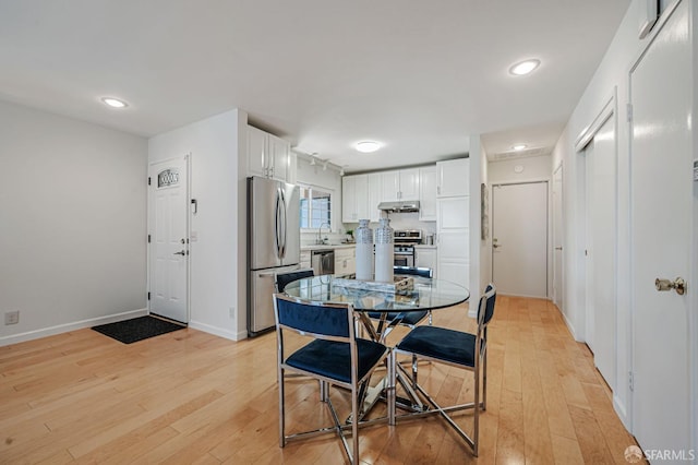 dining area featuring baseboards and light wood-type flooring