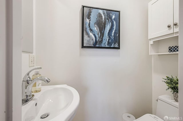 half bathroom featuring toilet and a sink