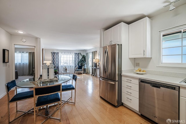 kitchen featuring open floor plan, light wood-style flooring, light countertops, white cabinets, and stainless steel appliances