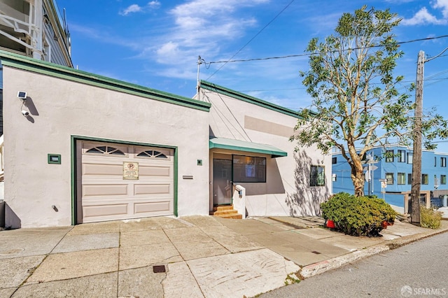 view of property featuring entry steps, driveway, and stucco siding