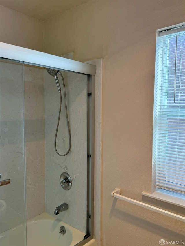 bathroom with bath / shower combo with glass door