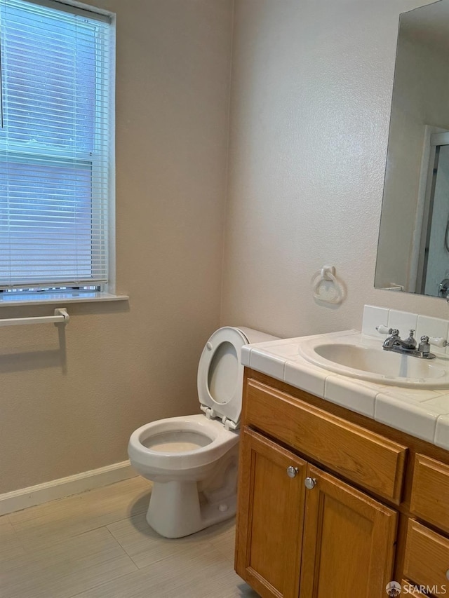 bathroom with toilet, vanity, and a healthy amount of sunlight