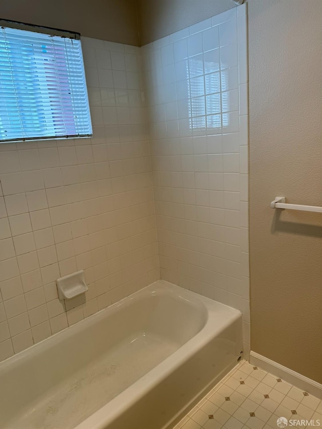 bathroom with tiled shower / bath combo and tile patterned flooring