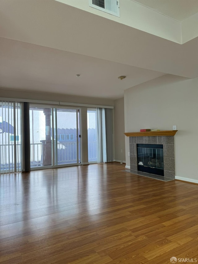 unfurnished living room featuring a tile fireplace and hardwood / wood-style floors