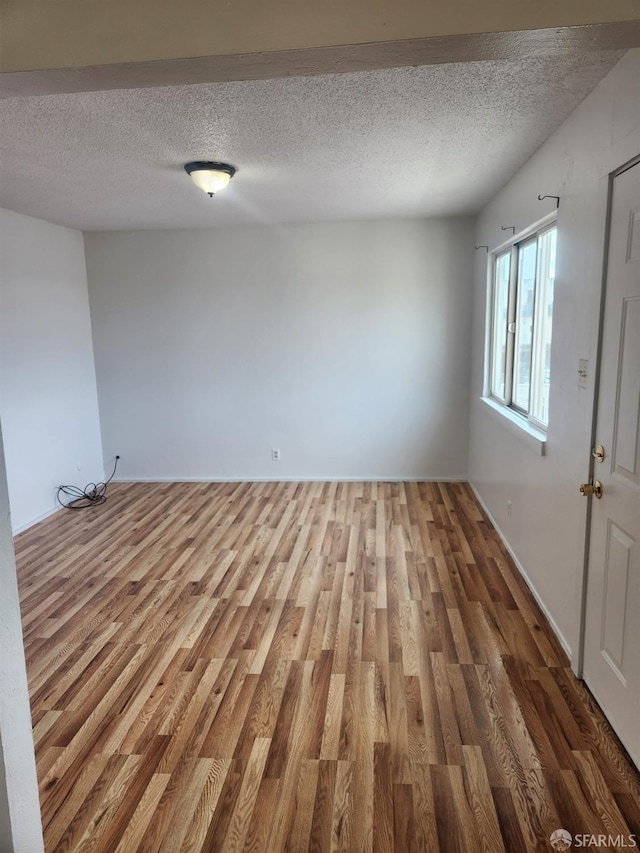 spare room with a textured ceiling and hardwood / wood-style flooring