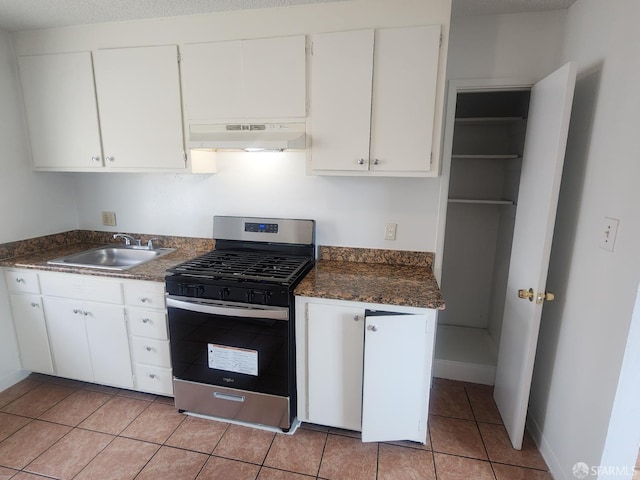 kitchen featuring light tile patterned flooring, sink, stainless steel gas stove, white cabinetry, and extractor fan