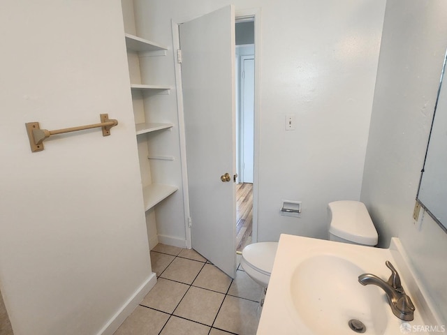 bathroom with toilet, sink, and tile patterned floors