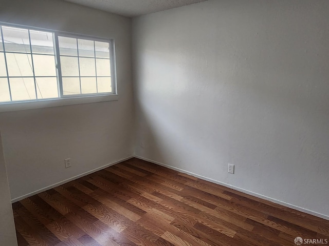 empty room featuring dark hardwood / wood-style floors and a textured ceiling