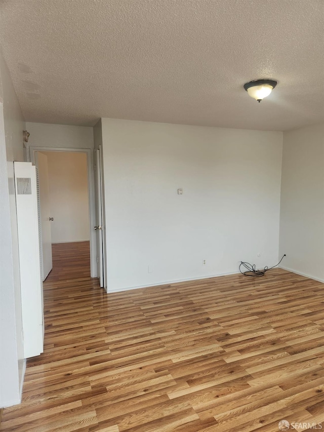 unfurnished room with light hardwood / wood-style floors and a textured ceiling