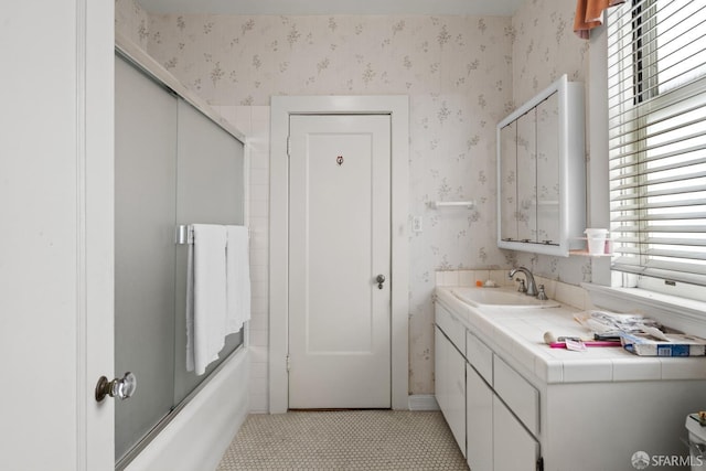 bathroom with wallpapered walls, vanity, and shower / bath combination with glass door