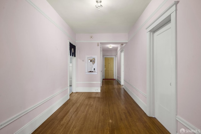 corridor with baseboards and wood finished floors