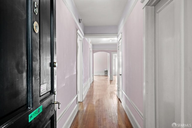 corridor with arched walkways and wood-type flooring