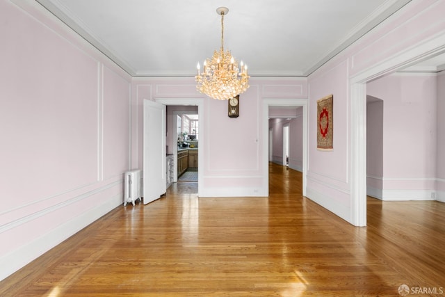 unfurnished dining area featuring a decorative wall, light wood-style flooring, radiator, and ornamental molding