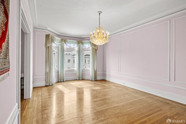 unfurnished dining area with light wood finished floors, an inviting chandelier, and a decorative wall